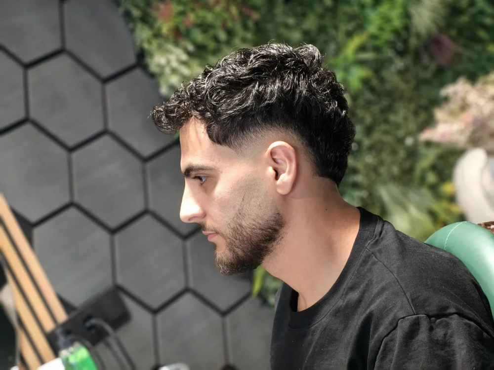 Curly top met strakke mid fade en scherpe contouren bij FreshAgain Barbers Hilversum
