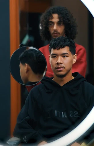 Klant met curly top en low fade in de spiegel
