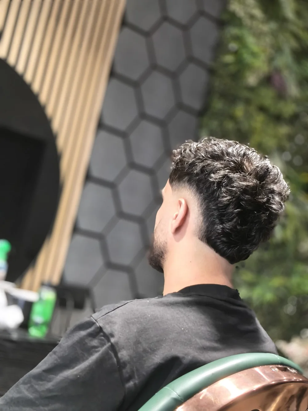 Achterkant van een taper fade met natuurlijke krullen, geknipt bij FreshAgain Barbers